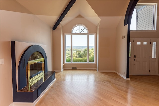 unfurnished living room with light hardwood / wood-style flooring, high vaulted ceiling, beamed ceiling, and a tile fireplace