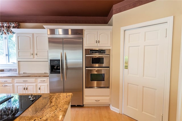 kitchen with light stone counters, stainless steel appliances, light hardwood / wood-style floors, and white cabinetry