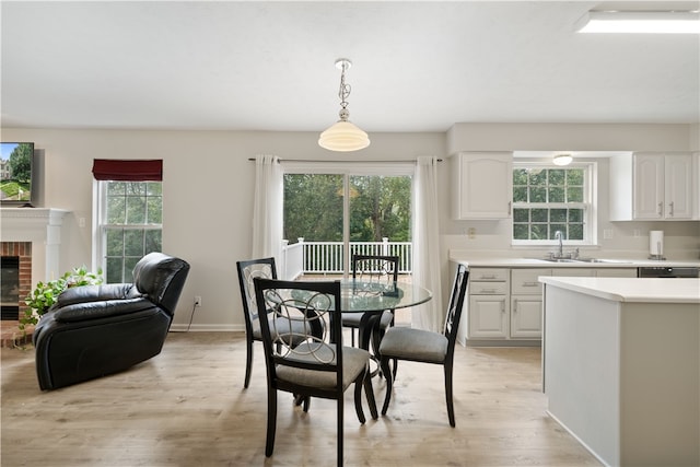 dining space featuring a brick fireplace, sink, and light hardwood / wood-style floors