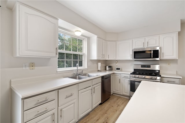 kitchen with stainless steel appliances, sink, light wood-type flooring, and white cabinets