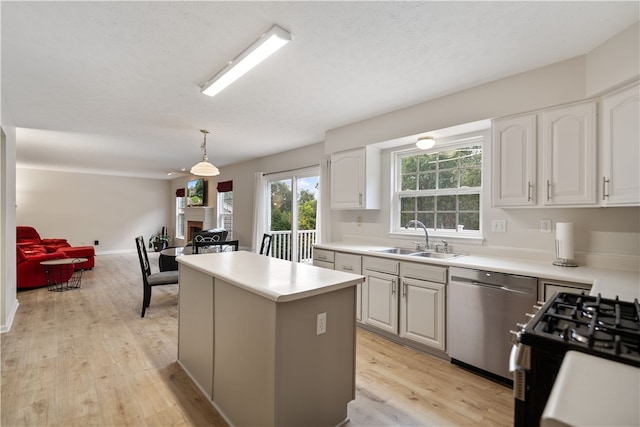 kitchen featuring stainless steel dishwasher, a center island, sink, light wood-type flooring, and white cabinets