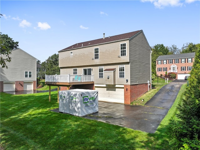 rear view of property featuring a garage, a yard, and a wooden deck