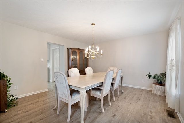 dining space with light hardwood / wood-style flooring and a notable chandelier