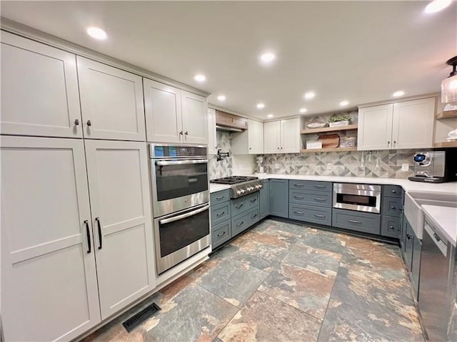 kitchen featuring gray cabinets, appliances with stainless steel finishes, backsplash, and white cabinetry