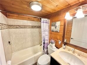 full bathroom featuring vanity, wood walls, wooden ceiling, shower / tub combo with curtain, and toilet