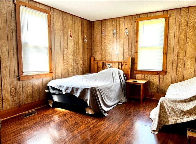 bedroom with dark wood-type flooring and wood walls