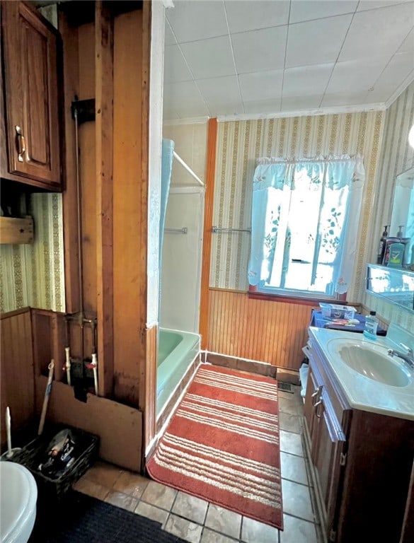 bathroom with bathtub / shower combination, tile patterned flooring, wooden walls, and vanity