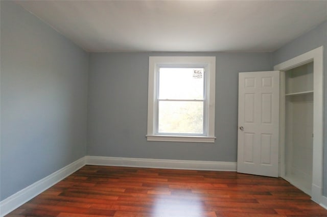 unfurnished bedroom with dark wood-type flooring and a closet