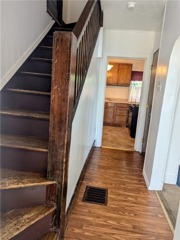 stairway with a textured ceiling and hardwood / wood-style floors