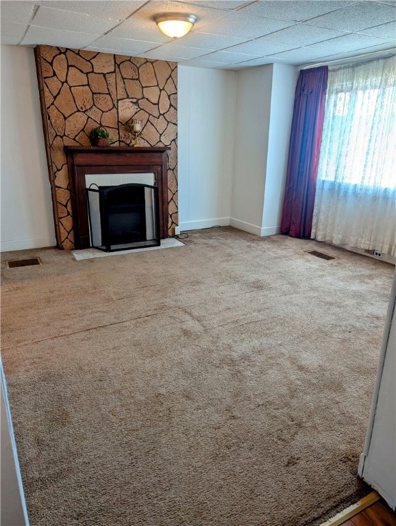 unfurnished living room with a paneled ceiling, carpet, and a fireplace