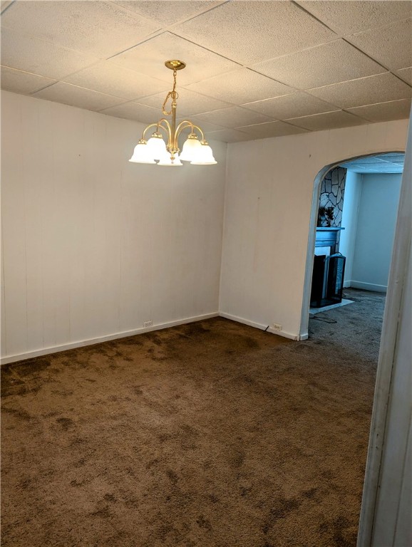 unfurnished room with a drop ceiling, a chandelier, and carpet