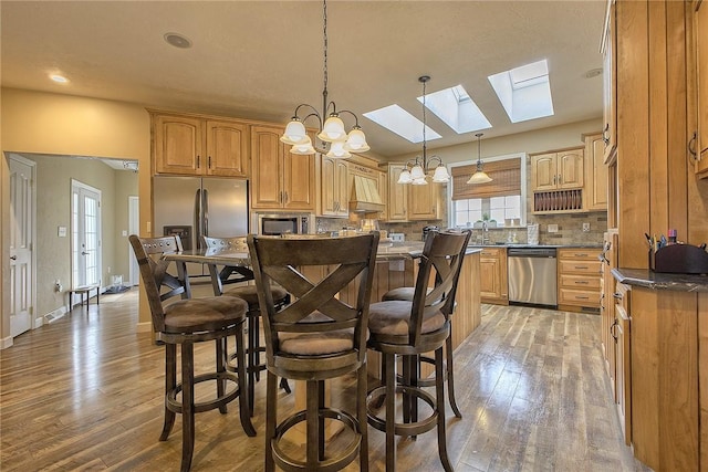 kitchen featuring a breakfast bar area, stainless steel appliances, a kitchen island, custom exhaust hood, and backsplash