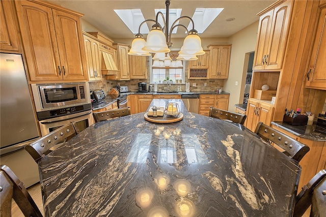 kitchen with appliances with stainless steel finishes, backsplash, a chandelier, and dark stone counters