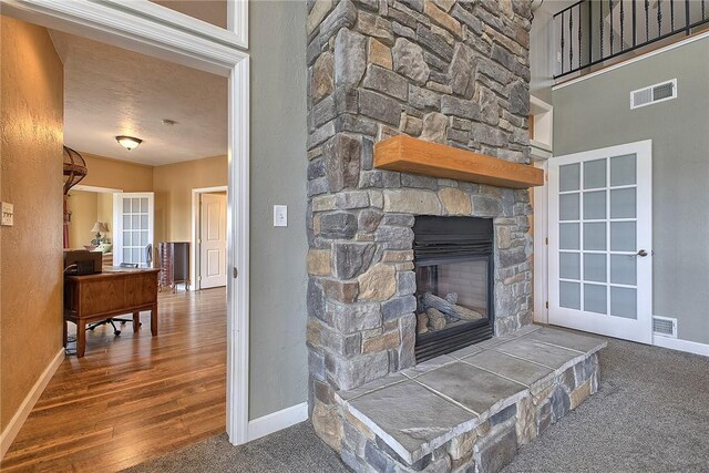 living room featuring wood-type flooring, a textured ceiling, and a stone fireplace