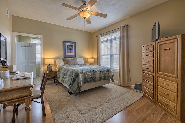 bedroom with ceiling fan, wood-type flooring, and a textured ceiling