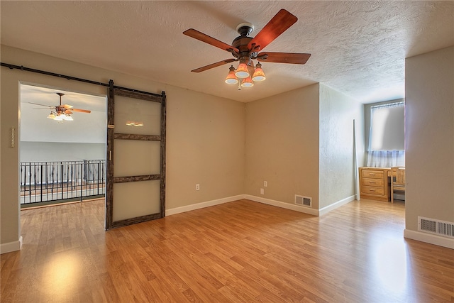 interior space featuring a textured ceiling, light hardwood / wood-style flooring, and a barn door