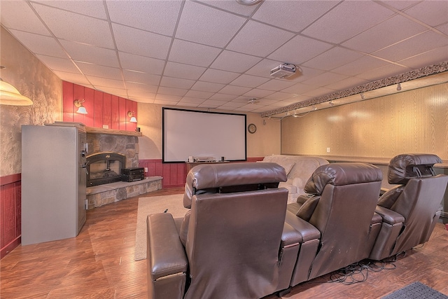 cinema featuring hardwood / wood-style flooring, a paneled ceiling, and a stone fireplace