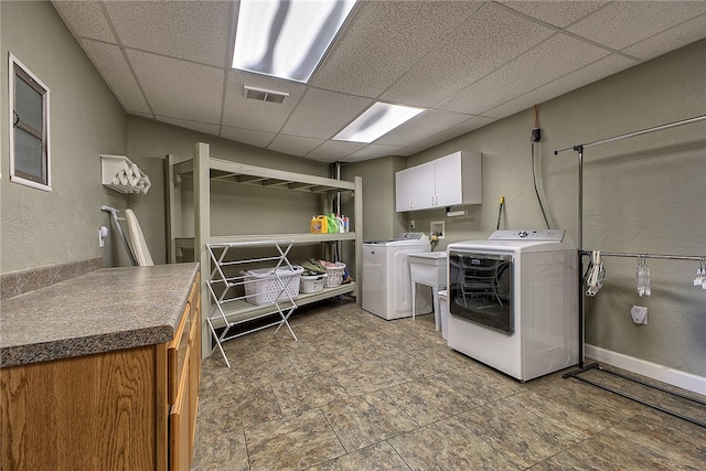 clothes washing area with cabinets and washing machine and clothes dryer