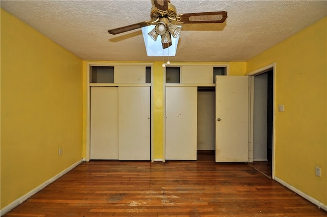 unfurnished bedroom with multiple closets, dark hardwood / wood-style flooring, ceiling fan, and a textured ceiling