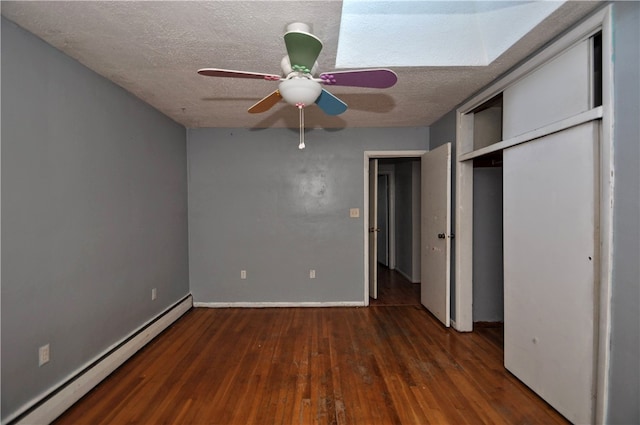 unfurnished bedroom featuring a textured ceiling, baseboard heating, ceiling fan, a closet, and dark hardwood / wood-style floors