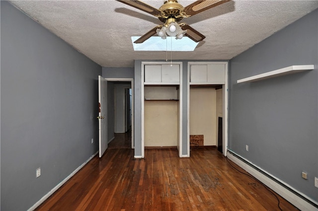 unfurnished bedroom with a textured ceiling, dark hardwood / wood-style flooring, a baseboard radiator, a skylight, and ceiling fan