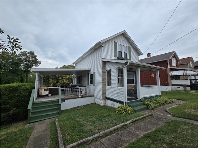 rear view of house featuring a yard and a porch