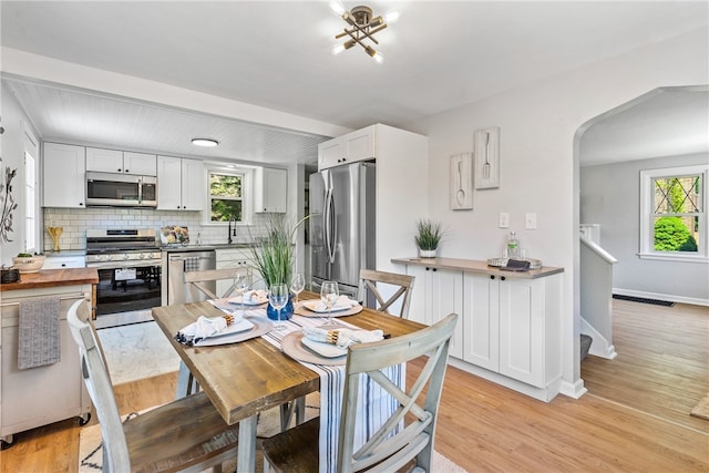 dining space with a healthy amount of sunlight, sink, and light wood-type flooring