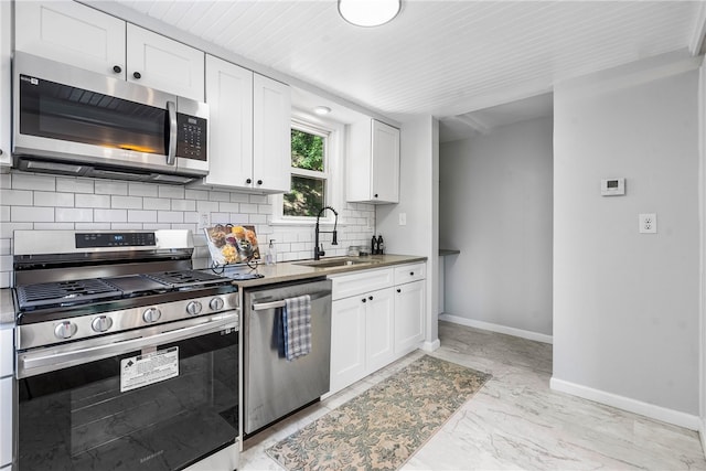 kitchen featuring appliances with stainless steel finishes, backsplash, sink, and white cabinets