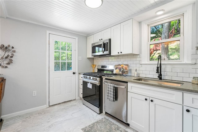 kitchen with dark stone countertops, white cabinetry, sink, decorative backsplash, and appliances with stainless steel finishes