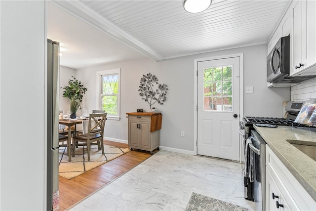 kitchen featuring beamed ceiling, light hardwood / wood-style flooring, stainless steel appliances, decorative backsplash, and white cabinetry