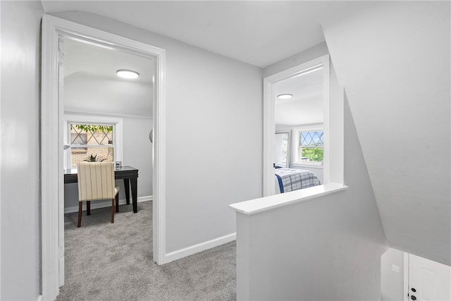 hallway with lofted ceiling and light carpet