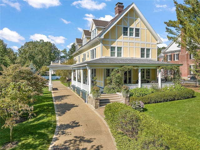 tudor house featuring covered porch and a front lawn