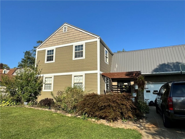 view of side of home with a yard, a garage, and metal roof