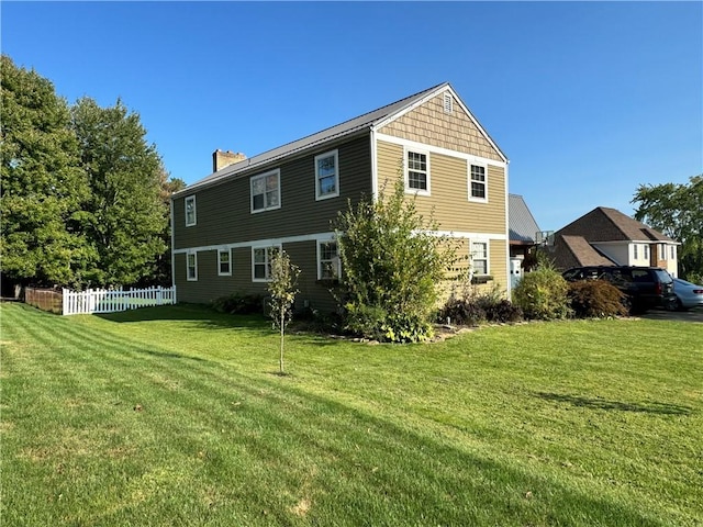 back of house with a lawn, a chimney, and fence