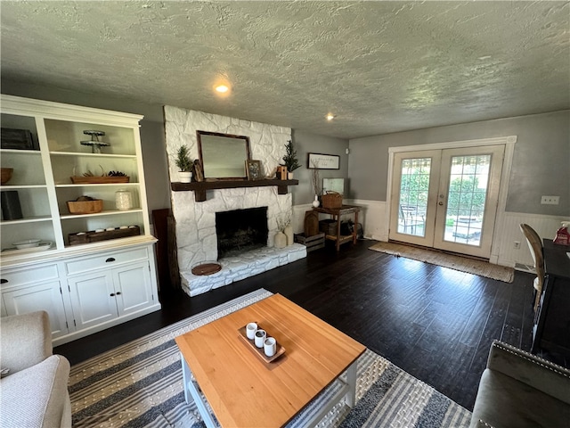 unfurnished living room featuring french doors, a textured ceiling, a stone fireplace, and dark hardwood / wood-style flooring