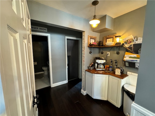 kitchen with butcher block countertops, white cabinetry, dark wood-type flooring, and hanging light fixtures