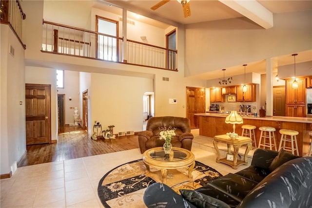 living room with light tile patterned floors, beamed ceiling, visible vents, and a towering ceiling