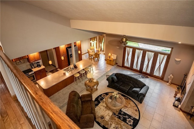 living area featuring baseboards, light tile patterned floors, a textured ceiling, and lofted ceiling