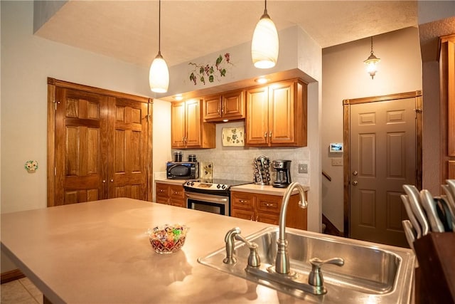 kitchen with stainless steel electric range oven, a sink, light countertops, pendant lighting, and backsplash