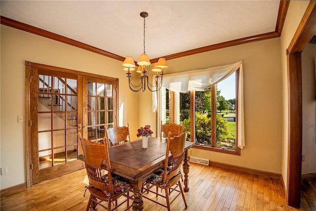 dining room with a chandelier, light wood-style flooring, baseboards, and ornamental molding