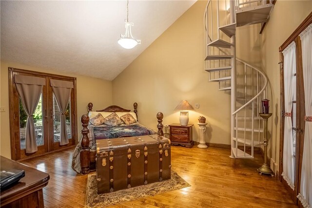 bedroom with french doors, baseboards, lofted ceiling, and hardwood / wood-style floors