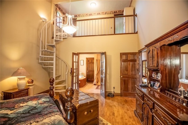 bedroom with baseboards, a towering ceiling, and light wood finished floors