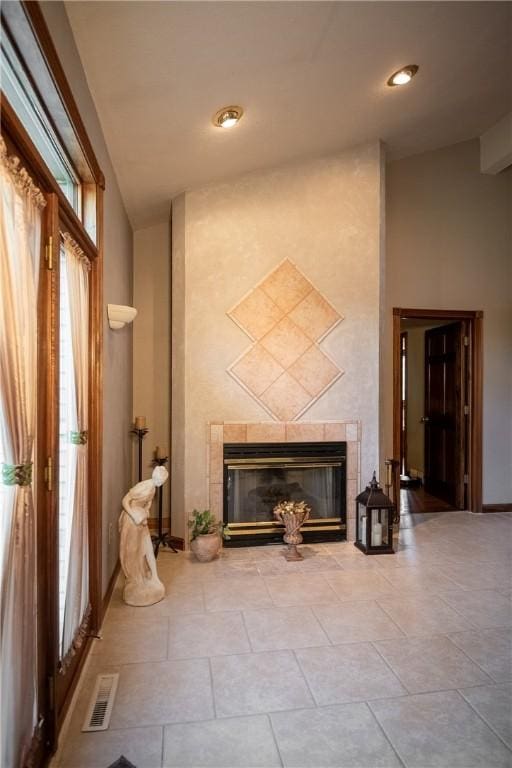 interior space featuring tile patterned flooring, visible vents, a fireplace, and baseboards