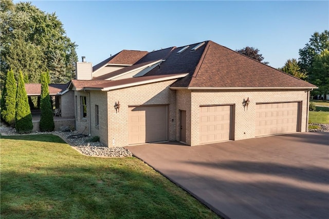 view of front of home featuring brick siding, concrete driveway, a front yard, a chimney, and an attached garage