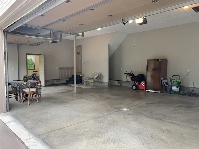 garage featuring a garage door opener and freestanding refrigerator