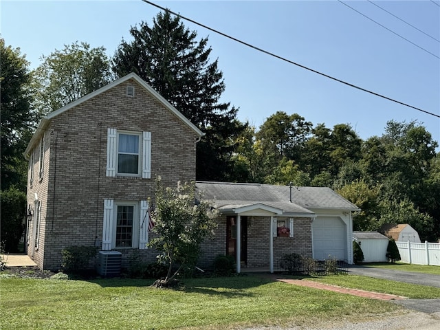 front facade with central air condition unit, a garage, and a front yard