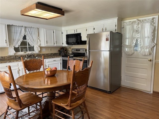 kitchen featuring white cabinets, dark stone countertops, hardwood / wood-style floors, appliances with stainless steel finishes, and sink