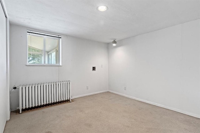 spare room with light carpet and radiator heating unit