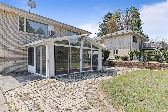 back of house featuring a sunroom, a patio, and a lawn