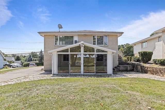 rear view of property with a sunroom and a yard